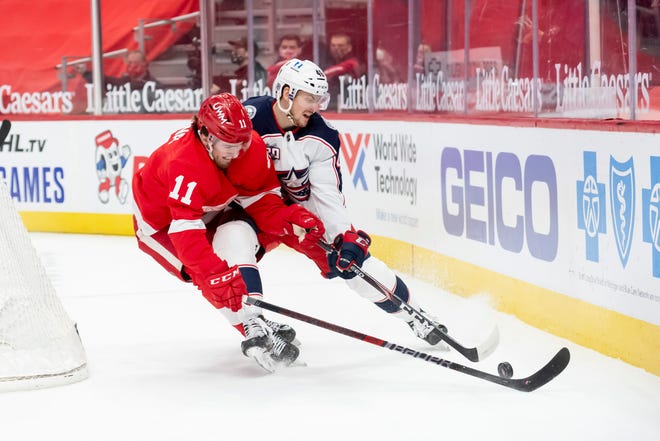 Detroit right wing Filip Zadina and Columbus defenseman Dean Kukan battle for the puck in the first period.
