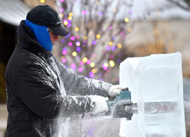 Finesse Ice owner Jeff Wolf uses an electric chain saw to cut away excess chunks of ice.