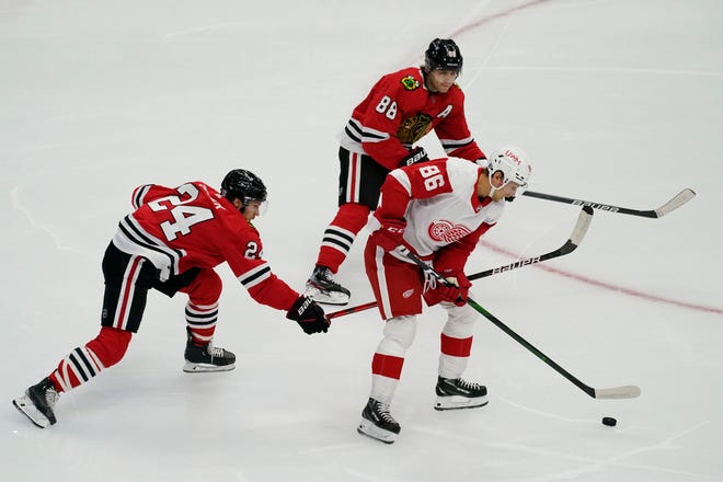 Detroit Red Wings center Mathias Brome (86) controls the puck against Chicago Blackhawks center Pius Suter, left, and right wing Patrick Kane during the first period of an NHL hockey game in Chicago, Friday, Jan. 22, 2021.