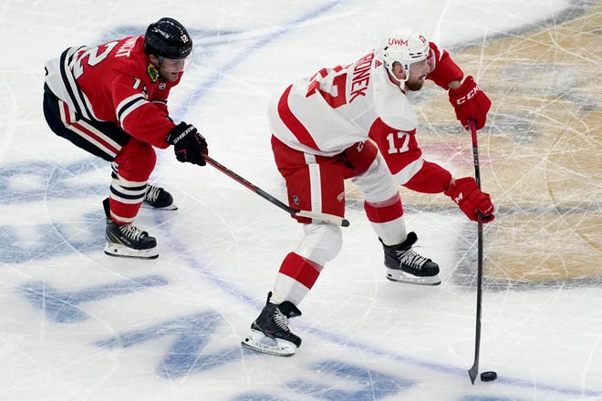 Detroit Red Wings defender Filip Hronek, right, looks to pass the puck as Chicago Blackhawks left wing Alex DeBrincat defends during the first period.