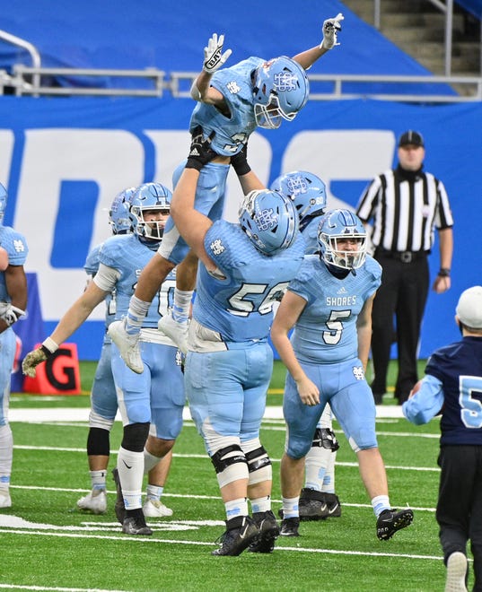Muskegon Mona Shores High Schools Ryan McNiff (30) is lifted up by teammate Kemper Mills (56) as they celebrate their win over Warren De La Salle High School in the fourth quarter.