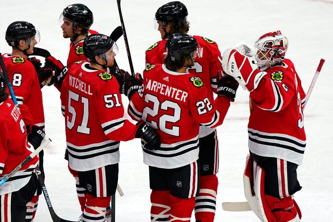 Chicago Blackhawks goalie Kevin Lankinen, right, celebrates with teammates after the team's 4-1 win over the Detroit Red Wings in an NHL hockey game in Chicago, Friday, Jan. 22, 2021.