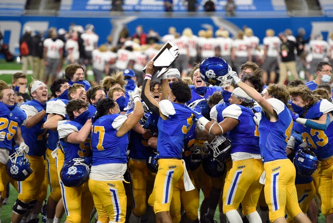 The Grand Rapids Catholic Central HS football team celebrate with their trophy after defeating Frankenmuth 48-21 in a Division 5 football final held at Ford Field