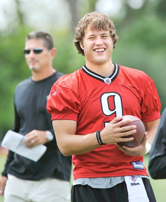 NFL No. 1 draft pick, quarterback Matthew Stafford, with Lions head coach Jim Schwartz in the background, loosens up before the start of practice in  Allen Park,  Michigan on July 31, 2009.