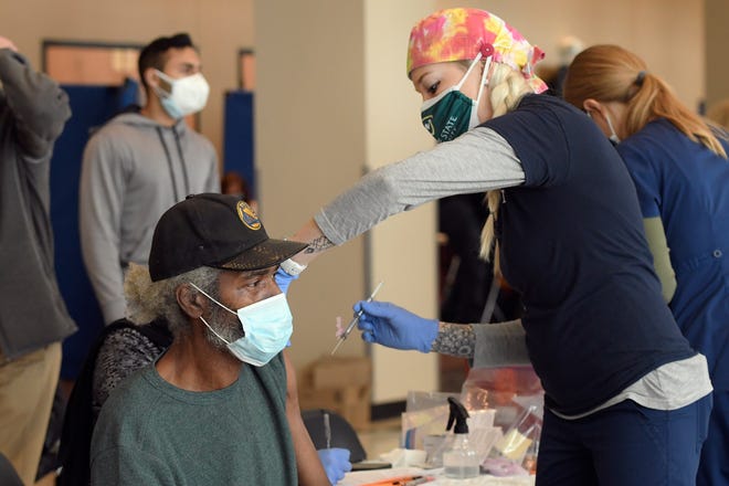 Registered Nurse Casey Mitroka, right, who is with the Wayne Health Mobile Health Unit, prepares to give the Moderna vaccine to Larry Dickinson at Second Ebenezer Church in Detroit, Saturday, Feb. 13, 2021.
