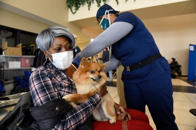 Bonita Hall of Detroit, seated, holds onto her dog, Zoey, as she gets the Moderna vaccine shot from Wayne Health Nurse Practitioner Dequanna Johnson at Second Ebenezer Church in Detroit, Saturday, Feb. 13, 2021.