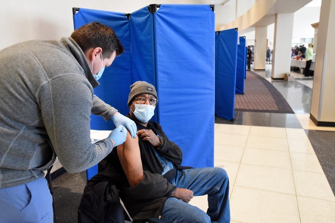 Michael Van Horn of Detroit, seated, gets the Moderna vaccine from Henry Ford Helath System RN Michael Garcia at Second Ebenezer Church in Detroit, Saturday, Feb. 13, 2021.