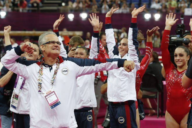 US women gymnastics team's coach John Geddert celebrates with the team after the US  won gold in the women's team of the artistic gymnastics event of the London Olympic Games on July 31, 2012 at the 02 North Greenwich Arena in London. Team US won gold, Team Russia took silver and Team Romania got bronze.