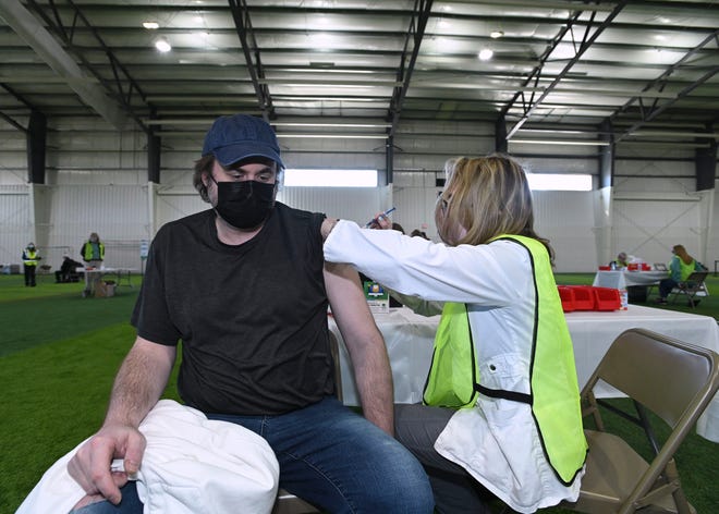Oakland County Public Health Nurse Margaret McCarthy, right, gives a vaccination shot to Brandon Opfermann of Waterford, Friday, April 2, 2021.