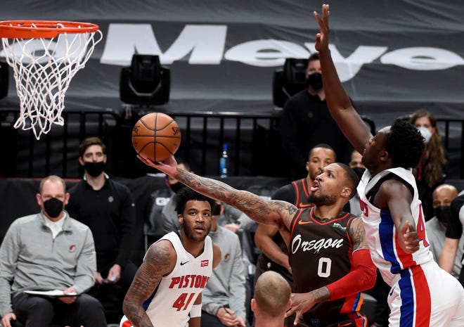 Portland Trail Blazers guard Damian Lillard (0) drives to the basket on Detroit Pistons forward Sekou Doumbouya, right, during the first half.