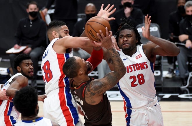 Portland Trail Blazers guard Damian Lillard, center, is fouled by Detroit Pistons guard Cory Joseph, left, as center Isaiah Stewart, right, helps on defense during the second half.