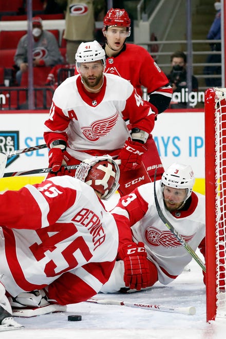 Carolina Hurricanes' Martin Necas (88), Detroit Red Wings' Luke Glendening (41) and Red Wings' Alex Biega (3) watch as Red Wings goaltender Jonathan Bernier (45) goes to cover the puck during the second period of an NHL hockey game in Raleigh, N.C., Monday, April 12, 2021.