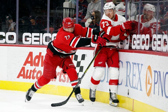 Carolina Hurricanes' Brett Pesce (22) battles with Detroit Red Wings' Adam Erne (73) during the first period.