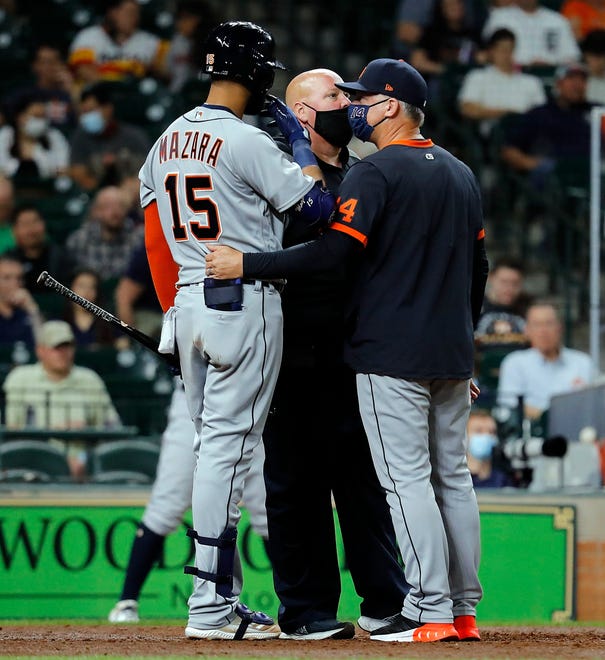Nomar Mazara #15 of the Detroit Tigers is looked at by the trainer and manager A.J. Hinch #14 after an injury at-bat in the fourth inning against the Houston Astros at Minute Maid Park on April 14, 2021 in Houston, Texas.
