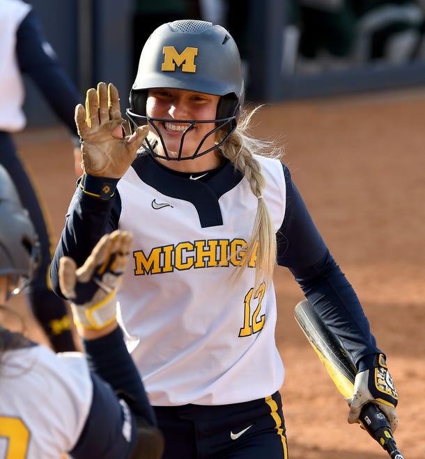 Michigan's Lauren Esman high fives a teammate after scoring on an RBI single from teammate Lou Allan in the fifth inning.