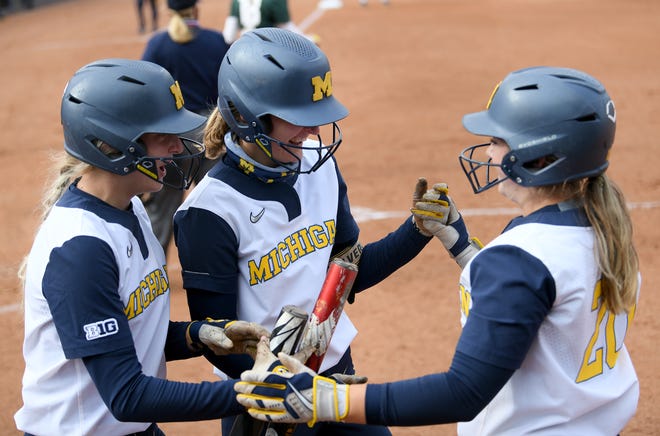 Michigan's Haley Hoogenraad, center, celebrates with teammates, Lauren Esman, left, and Hannah Carson, after blooping a hit down the right field line and then circling the bases for an inside-the-park two run homer in the second inning.