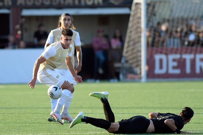 Detroit City FC defenseman Kevin Venegas, left, takes the ball upfield past a fallen L.A. Force defender in the first half.