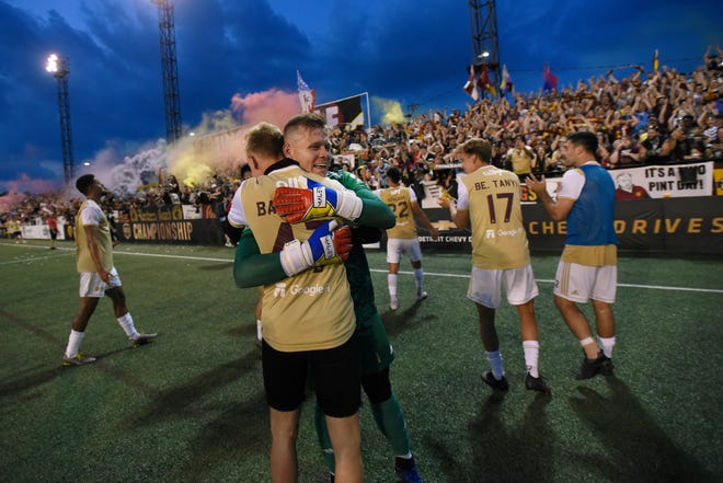 Detroit City FC goalkeeper Nate Steinwascher, back, and forward Barnabas Tanyi hug after defeating the L.A. Force, 1-0.