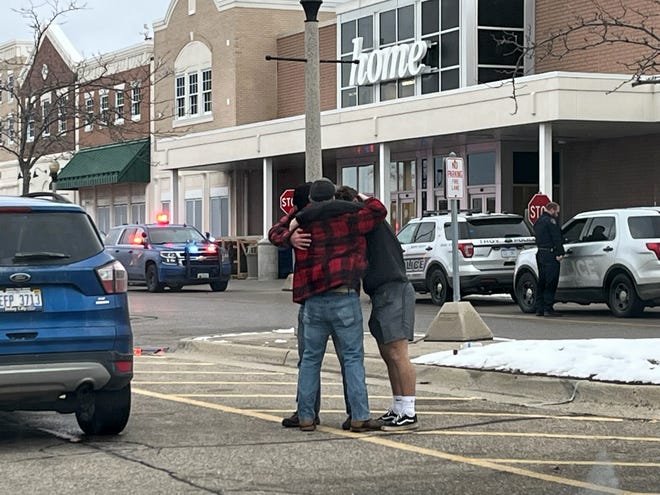 Students and adults hug in the parking lot at the Meijer store in Oxford after a school shooting at Oxford High School on Tuesday, Nov. 30, 2021.