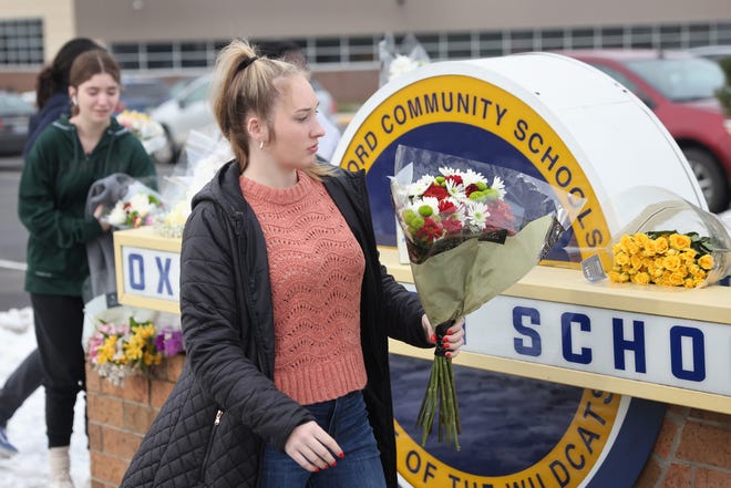 People bring flowers to a makeshift memorial outside of Oxford High School on Wednesday, Dec. 1, 2021, a day after four students were killed and seven others, including a teacher, were wounded in a mass shooting.