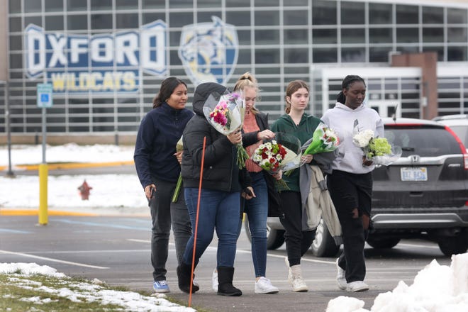 People bring flowers to a makeshift memorial outside of Oxford High School on Wednesday, Dec. 1, 2021, a day after four students were killed and seven others, including a teacher, were wounded in a mass shooting.