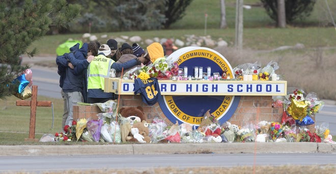 A Chaplin hugs students in prayer at a memorial at the entrance to Oxford High School on Thursday, December 2, 2021.