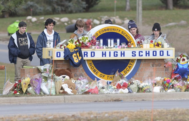 Students stand in unity at a memorial at the entrance to Oxford High School on Thursday, Dec. 2, 2021. Four students were killed and seven others, including a teacher, were injured when sophomore Ethan Crumbley, 15, allegedly opened fire inside with a pistol in the school.