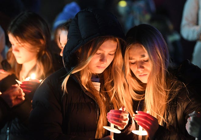 Hadley Socha, 15, center, and Lilla Bonner, 15, right, light candles during a vigil in Children’s Park in Lake Orion on Thursday, Dec. 2, 2021 in support of those involved in the Oxford High School shooting on Tuesday.  Socha said. "People should not be scared to have to go to school every single day. It should be a safe place where people want to go to and learn."