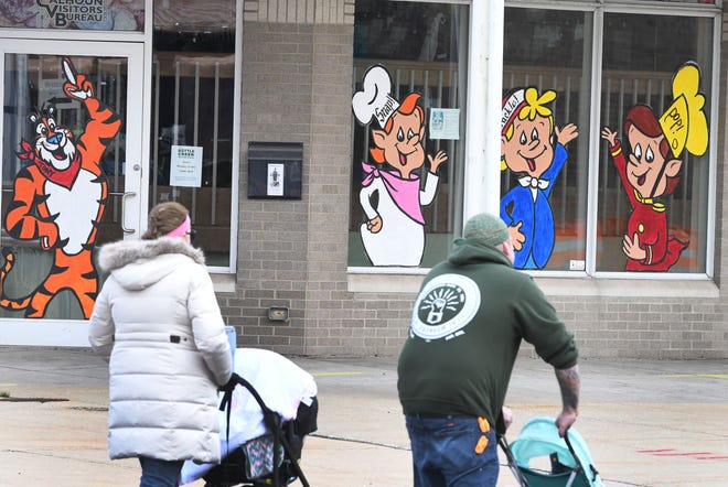 Rally attendees for striking Kellogg's workers go past a Battle Creek 'Welcome Center' with characters from the Kellogg cereal company in downtown Battle Creek after listening to U.S. Senator Bernie Sanders speak.