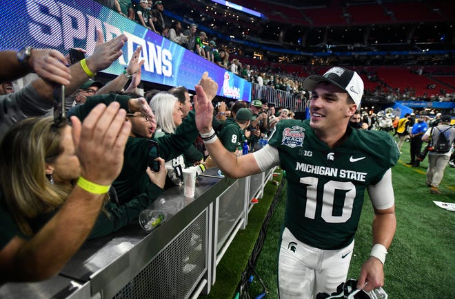 Michigan State quarterback Payton Thorne slaps hands with Spartan fans still in the building after the MSU Peach Bowl victory.