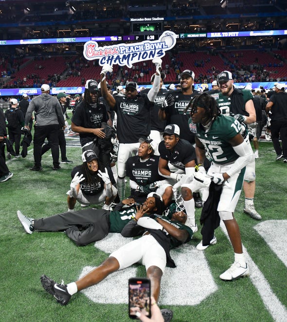 MSU players pose for pictures after winning the 2021 Peach Bowl over Pitt.