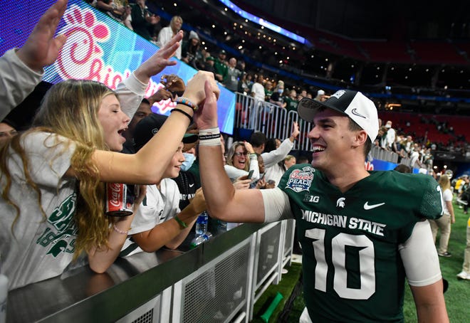 Michigan State quarterback Payton Thorne slaps hands with Spartan fans still in the building after the MSU Peach Bowl victory.