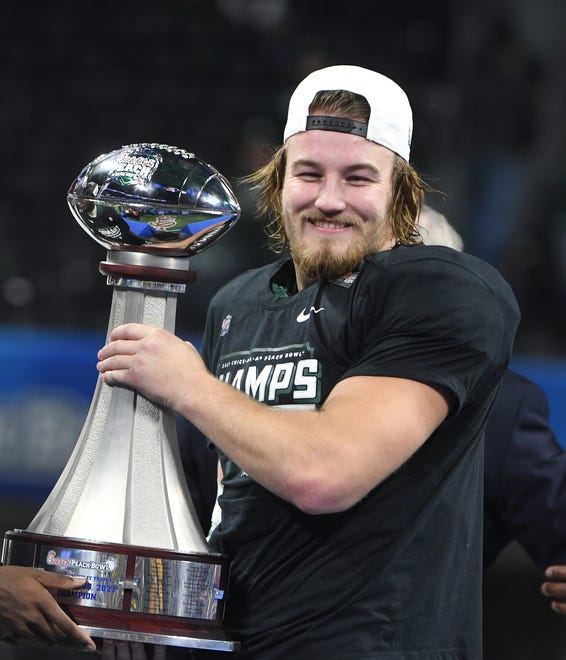 Michigan State's Cal Haladay, who won the Peach Bowl defensive player of the game, poses with the Peach Bowl trophy after the victory over Pitt.