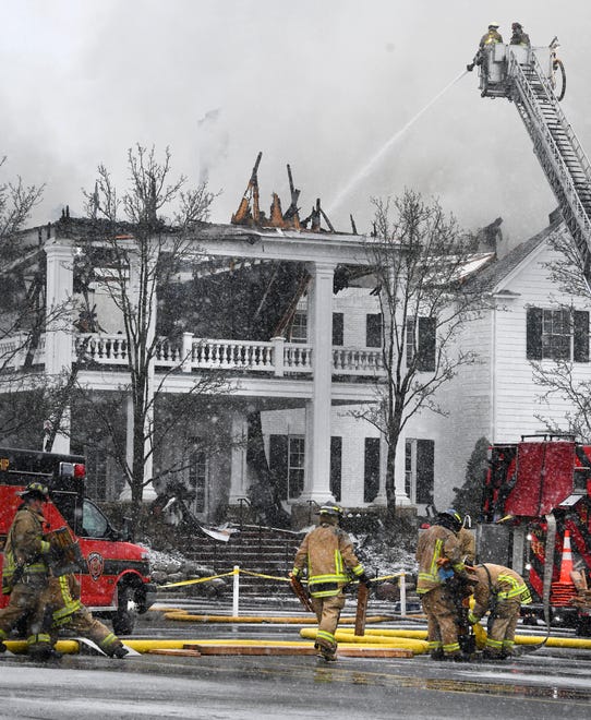 Snow falls and wind blows as firemen continue to work on putting out the fire, still smoldering with smaller flareups, at the main building at Oakland Hills Country Club.