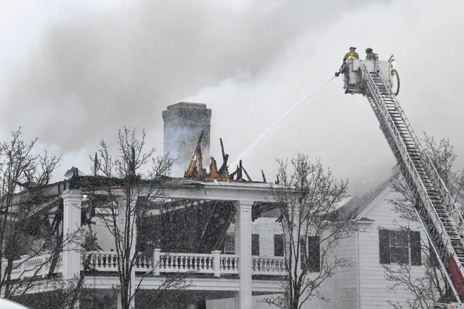Snow falls and wind blows as firemen continue to work on putting out the fire, still smoldering with smaller flareups, at the main building at Oakland Hills Country Club.